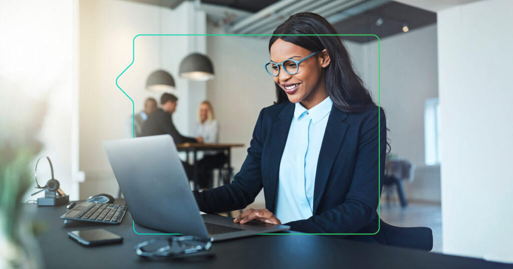 a smiling woman working at a laptop with a synergy learning brand device around her